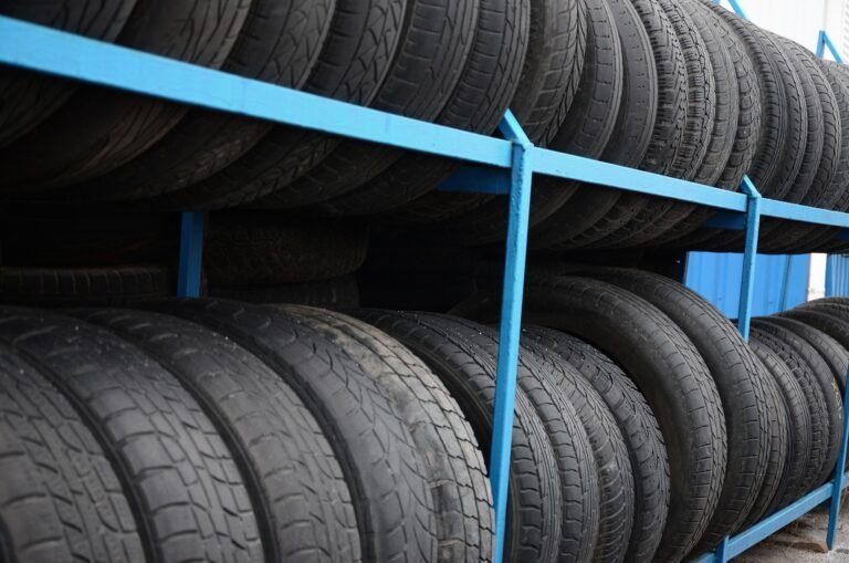 Rack with variety of car tires in automobile store. Many black tires. Tire stack background